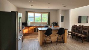 Une cuisine moderne avec un îlot central en bois, des tabourets de bar et une grande fenêtre.