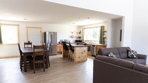 Une cuisine moderne avec des meubles en bois, un îlot central et un coin repas comprenant une table et des chaises.
