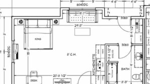 Plan d’étage d’une chambre d’hôtel comprenant un grand lit, un bureau, une salle de bain et un patio couvert.