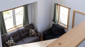 A high-ceiling room with four windows, a sofa, and a wooden bench.