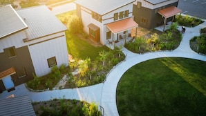 A modern building with a curved driveway, a covered patio area, and a well-maintained lawn.