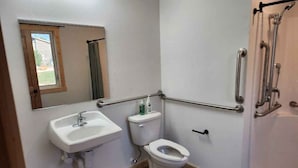 Ein kleines, barrierefreies Badezimmer mit Waschbecken, Toilette und Dusche.