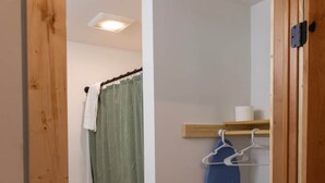 Un couloir étroit avec un cadre de porte en bois, un rideau vert, une serviette blanche et un vêtement bleu suspendu à un portant.