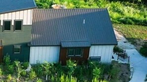 Une maison moderne à deux étages, dotée d’un toit en pente, entourée d’une pelouse bien entretenue et d’une allée incurvée.