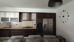 Una cocina moderna con armarios oscuros, un refrigerador de acero inoxidable y un reloj de pared.