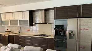 Una cocina moderna con armarios oscuros, horno empotrado y refrigerador con dispensador de agua.