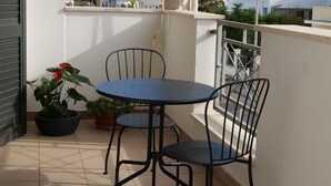 A balcony with a table and chairs, potted plants, and a view of buildings in the background. - Independent apartments/rooms  (Otranto)