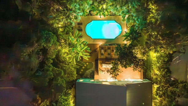 Un bâtiment doté d’une piscine, le tout entouré d’une végétation luxuriante.