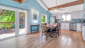 Une cuisine spacieuse dotée d’un plancher en bois, de meubles blancs et d’un coin repas avec une table et des chaises.