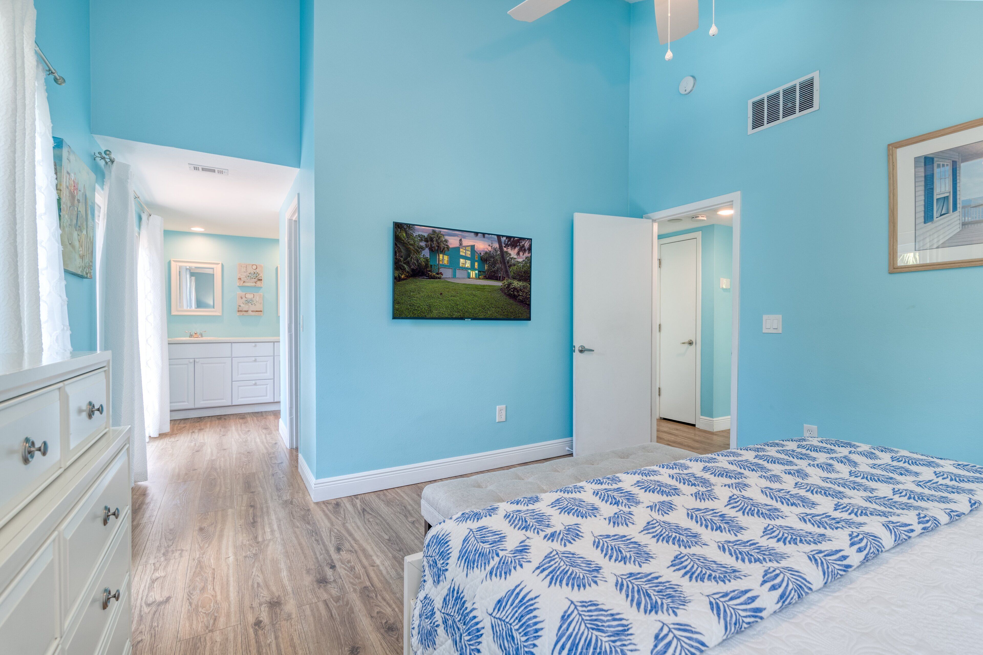 A bedroom with a bed, a door, and a hallway leading to a bathroom.