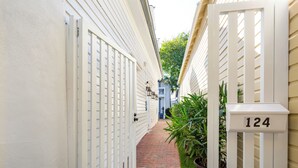 A narrow brick pathway flanked by white fences with a mailbox marked "124". - Custom House Inn (Key West)