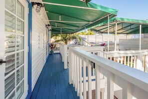 A covered porch with a blue floor, white railings, and a green canopy. - Custom House Inn (Key West)