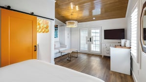 A bedroom with a bed, a desk, a chair, and a television. - Custom House Inn (Key West)
