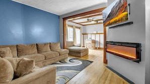 Ein modernes Wohnzimmer mit einer großen Couch, einem Kamin und einem an der Wand befestigten Fernseher.