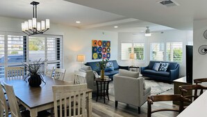 A spacious living area with a dining table, chairs, sofas, and a colorful abstract painting. - Fully remodeled winter home away from home - Steps away from beach and pools (St. Augustine Beach)