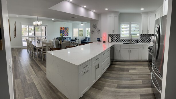 A modern kitchen with white cabinetry, a large island, and a stainless steel refrigerator. - Fully remodeled winter home away from home - Steps away from beach and pools (St. Augustine Beach)
