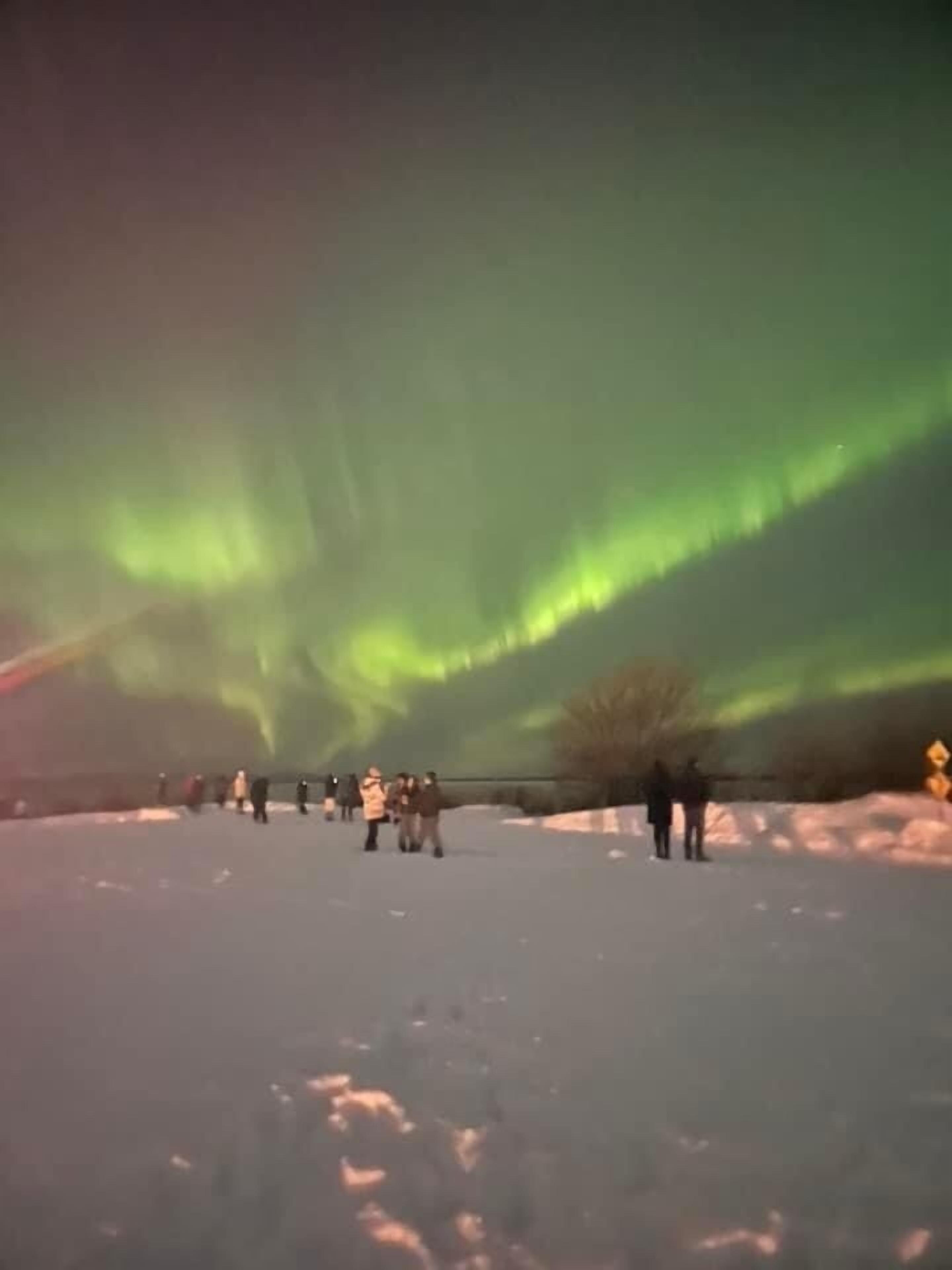 Et snøklædt landskab med mennesker, der betragter nordlys.