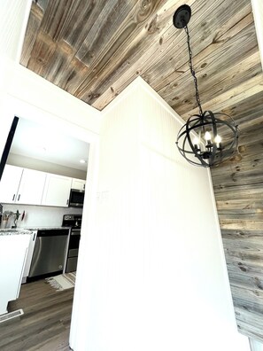 Een moderne keuken met witte kasten, roestvrijstalen apparatuur en een houten plafond.