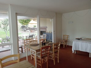 A dining area with a large table and multiple chairs, a small table with a white tablecloth, and a view of the outdoor patio area. - Casa di Palaia (Greve in Chianti)
