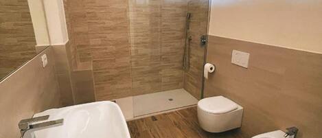 A modern bathroom with a large sink, a bidet, and a glass-enclosed shower.