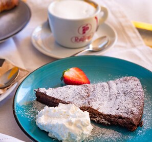 A slice of chocolate cake with whipped cream and a strawberry on a blue plate. - Casa di Palaia (Greve in Chianti)