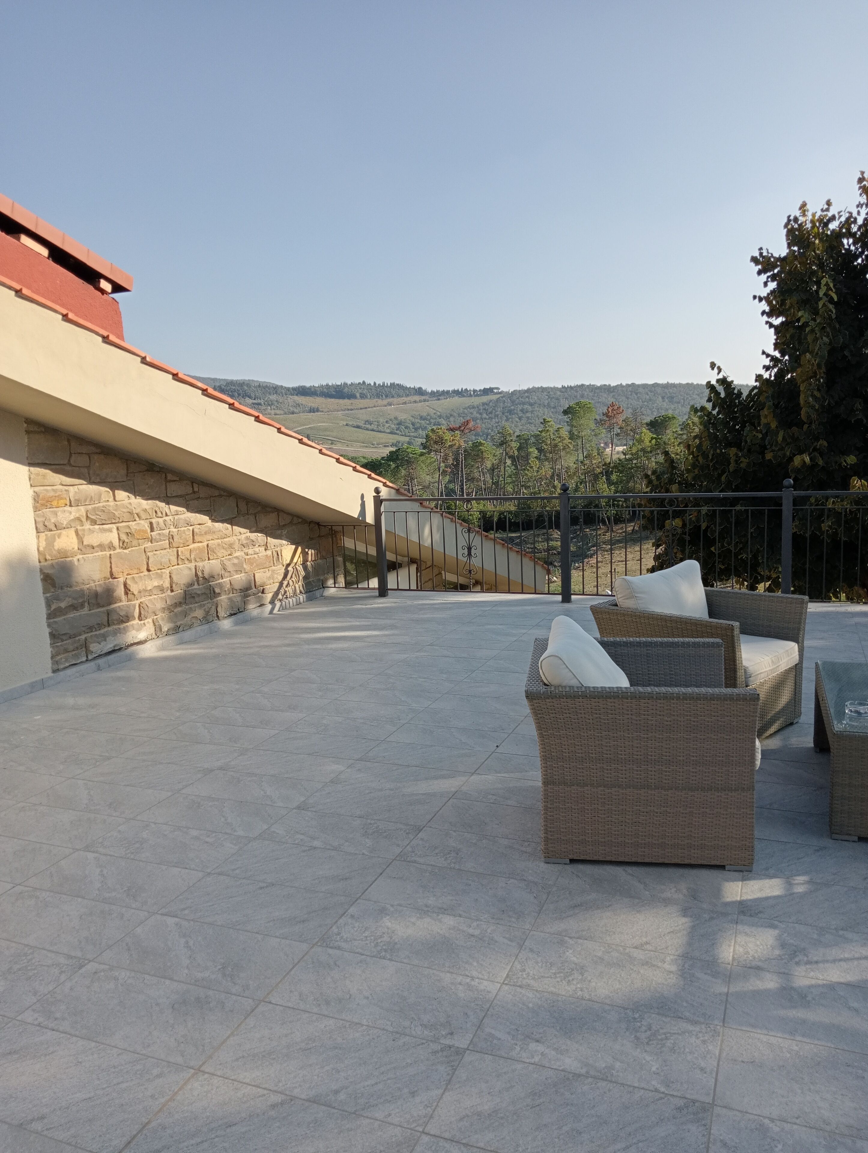 A patio with stone flooring, wicker furniture, and a view of hills.