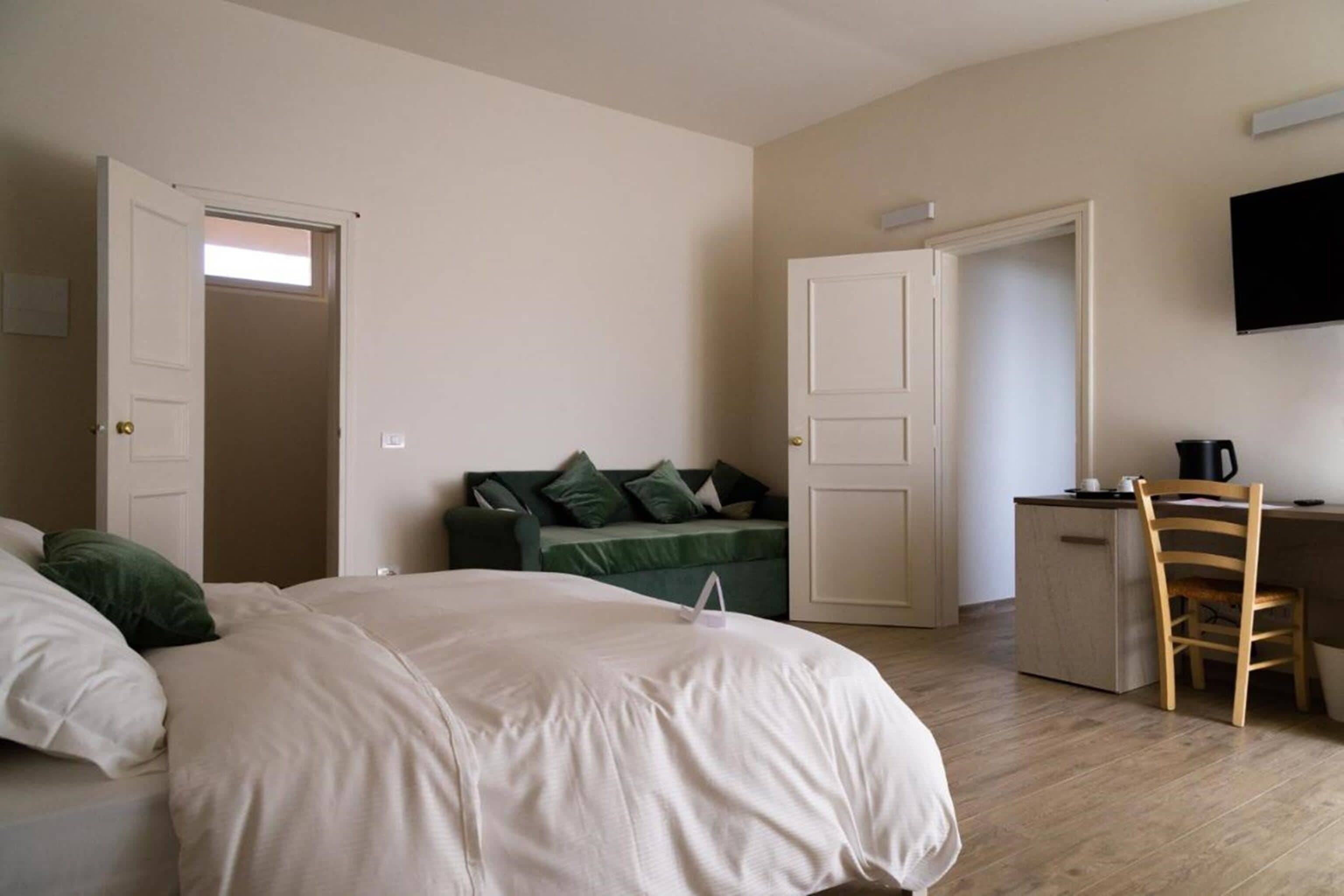A bedroom with a bed, a desk, a chair, and a television on the wall.