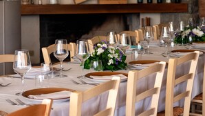 A dining area with a long table set for a meal, chairs, wine glasses, and a fireplace with a framed artwork above. - Casa di Palaia (Greve in Chianti)