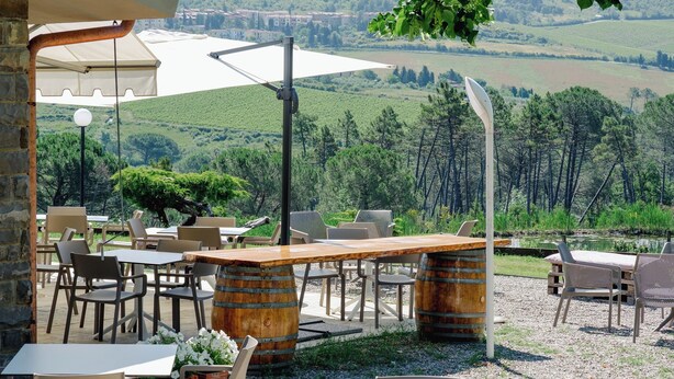 An outdoor seating area with tables and chairs, a wooden bar, and a view of the countryside. - Casa di Palaia (Greve in Chianti)
