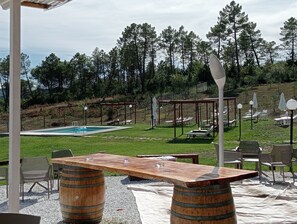 A pool area with lounge chairs and a wooden table, surrounded by a grassy area and trees. - Casa di Palaia (Greve in Chianti)