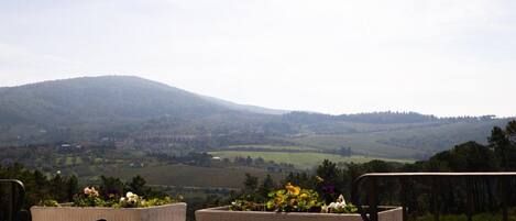 A table and chairs set outdoors with a view of rolling hills and a lake.