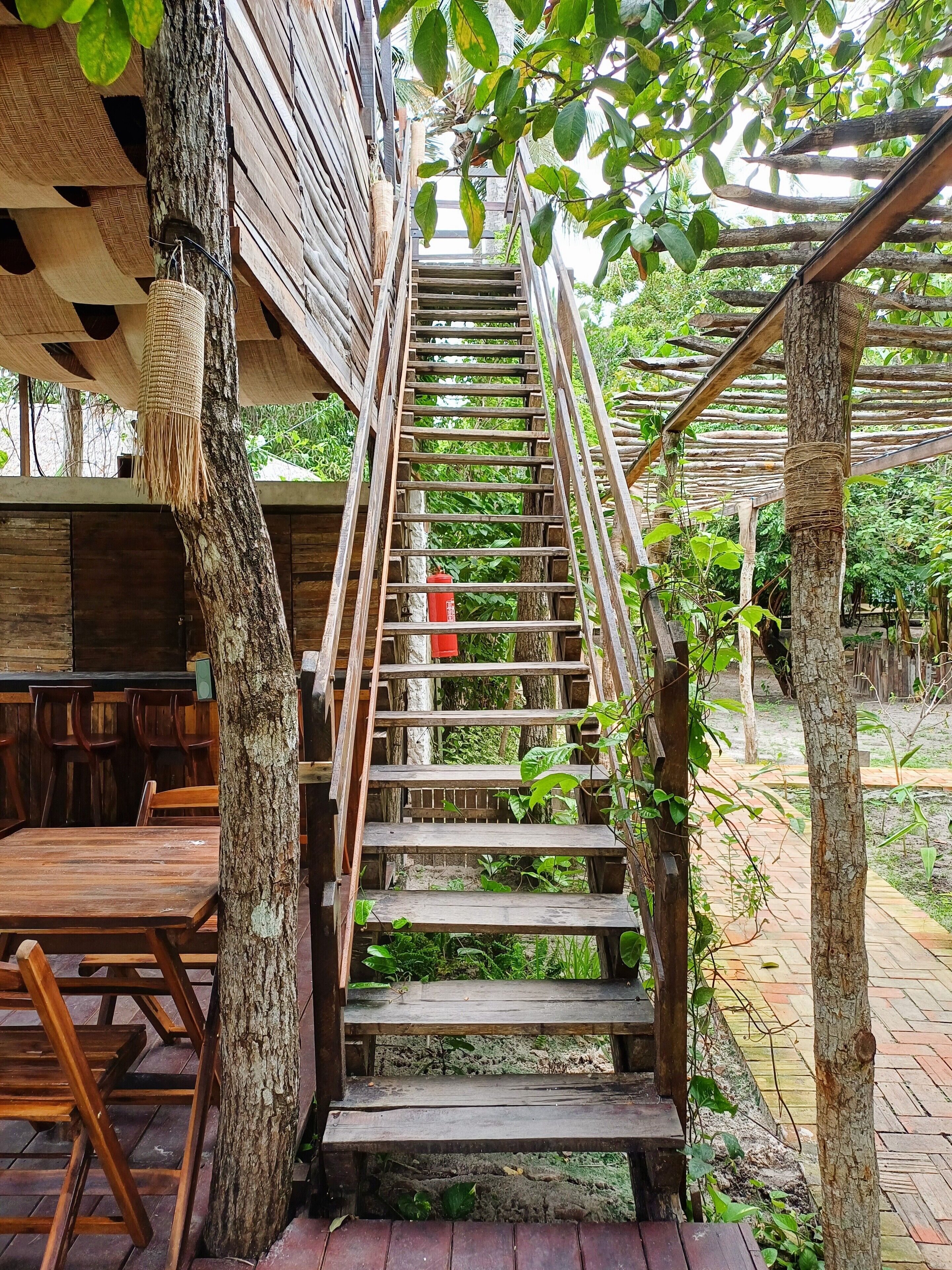 A wooden staircase leading to a covered seating area with wooden tables and chairs.