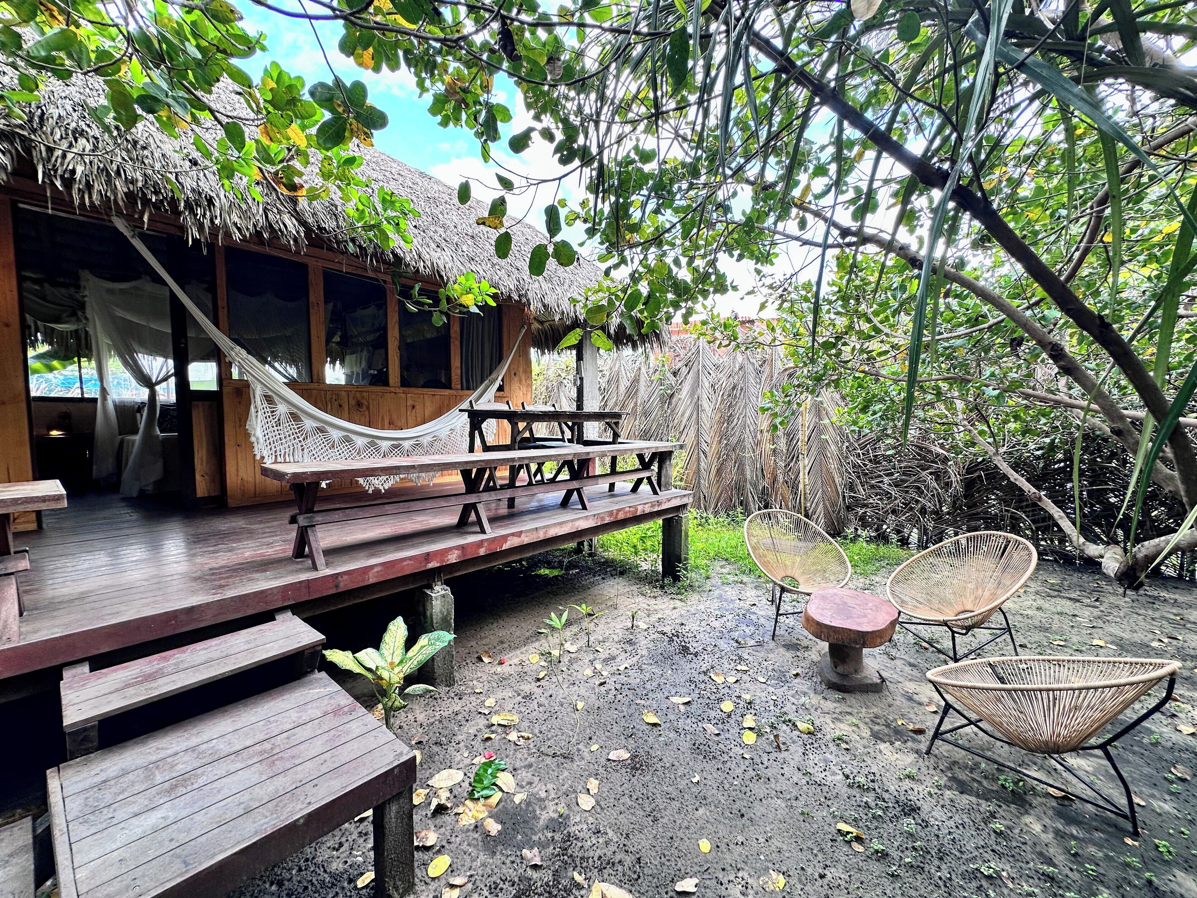 A wooden deck with a hammock, picnic table, and wicker chairs.