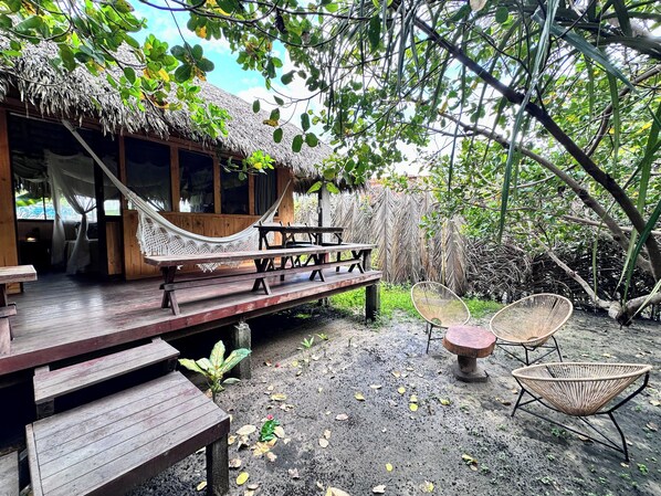 A wooden deck with a hammock, picnic table, and wicker chairs. - Vila do Junco (Santo Amaro do Maranhão)