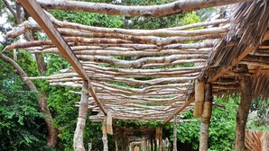 En brobelagt sti, der fører gennem en have med en pergola over sig.