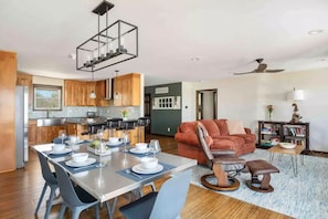 A modern kitchen with wooden cabinets, a dining table set for four, and a ceiling fan.