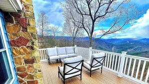 Eine Terrasse mit Steinmauer, weißer Geländer und Blick auf eine Berglandschaft.