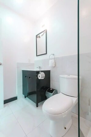 Ein modernes Badezimmer mit Toilette in Weiß, Waschtisch in Schwarz und einem gerahmten Schild an der Wand.