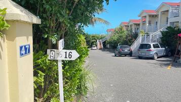 A residential street with houses, a street sign, and parked cars.