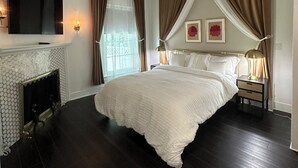 A bedroom with a large bed, a flat-screen TV mounted on the wall, a fireplace, and a nightstand with a lamp. - Perfect for family/corporate, Strategic location, 2mi Yale, 2.8 mi Airport,  (New Haven)