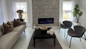 A modern living room with a sofa, two armchairs, a coffee table, a flat-screen TV, and a stone accent wall. - Perfect for family/corporate, Strategic location, 2mi Yale, 2.8 mi Airport,  (New Haven)