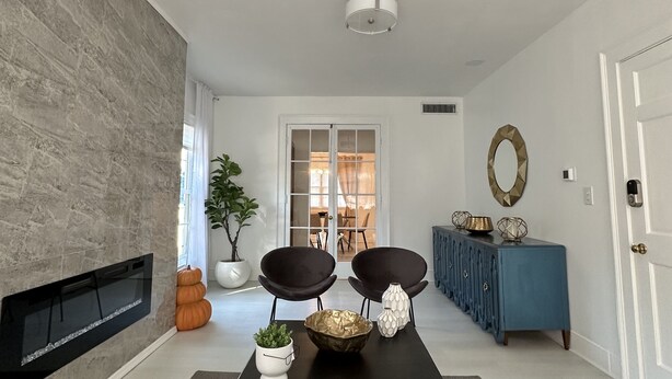A modern living room with a fireplace, a black coffee table, two black armchairs, a blue console table, and a large potted plant. - Perfect for family/corporate, Strategic location, 2mi Yale, 2.8 mi Airport,  (New Haven)