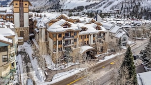A snow-covered resort with a prominent tower and multiple buildings with balconies. - Boutique Resort in Vail Village -  3 BR - 3BA Residence at The Sebastian (Vail)