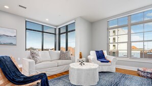A modern living room with a white sofa, a blue patterned rug, and a round coffee table. - Custom Suite over Target - Downtown AU 209 (Auburn)