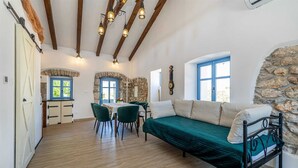 A cozy room with a bed, a table with chairs, and a stone wall. - Holiday house KUNTENTA with private pool and jacuzzi (Skrbčići)
