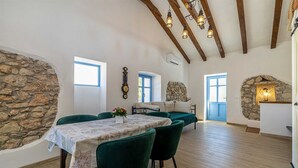 A dining area with a table set for two, a stone wall, and a rustic wooden ceiling. - Holiday house KUNTENTA with private pool and jacuzzi (Skrbčići)