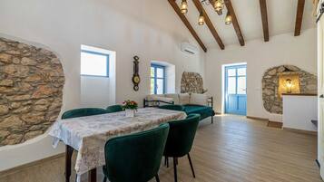 Un coin repas avec une table dressée pour deux personnes, un mur en pierre et un plafond en bois rustique.