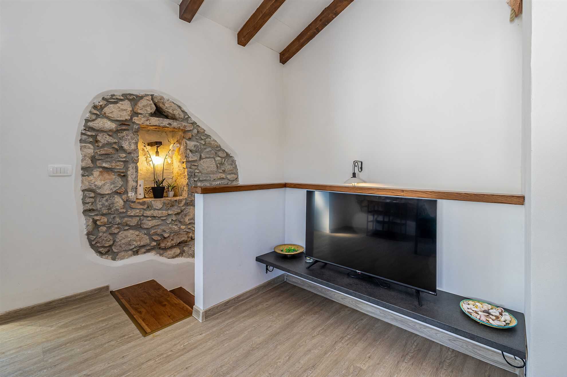 A modern kitchen with a stone accent wall, built-in stove, and wooden beams.