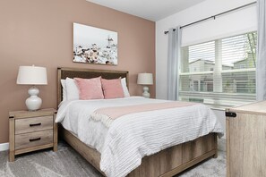 Un dormitorio con cama de madera, dos mesitas de noche con lámparas, un ventanal con persianas y una obra de arte colgada en la pared.