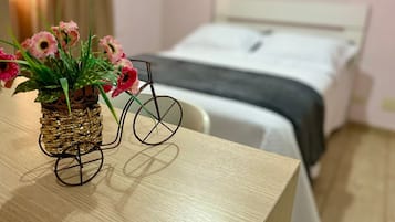 A bed, a bicycle, and a vase with flowers on a table.
